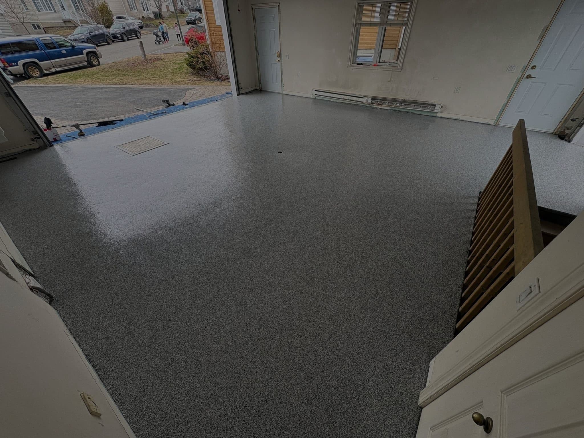 Garage fini en flocons de vinyle gris, porte ouverte sur l'entrée